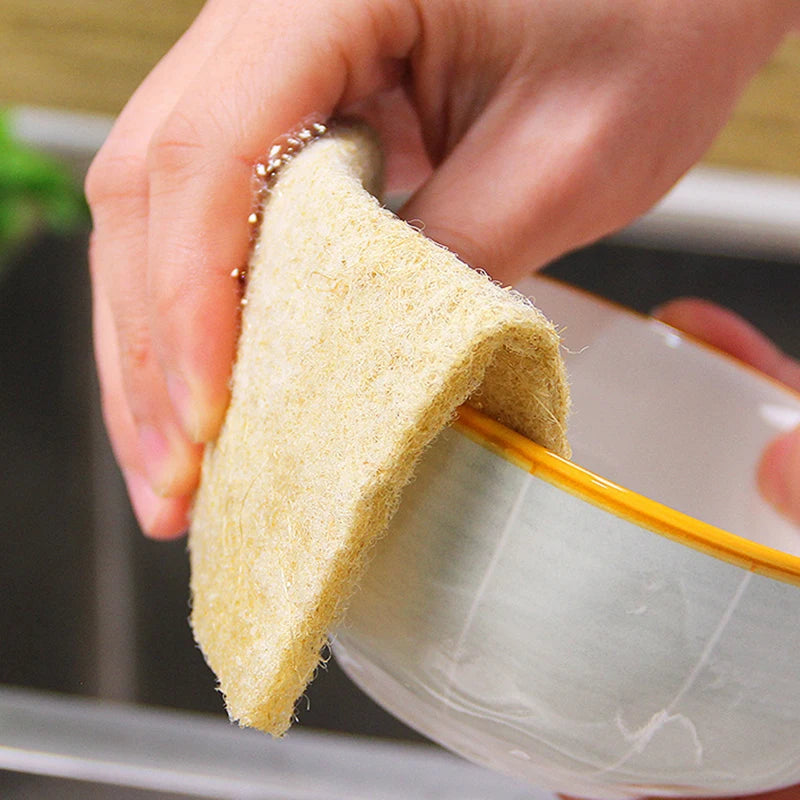 Person using eco-friendly cleaning sponges on a bowl in the kitchen, promoting sustainable cleaning solutions.